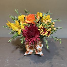 Mixed bouquet with orange rose, burgundy chrysanthemum, and yellow flowers in a glass vase