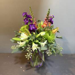 Colorful bouquet in a glass vase with purple, white, and green flowers