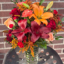 Mixed bouquet with lilies, roses, and carnations in a clear glass vase