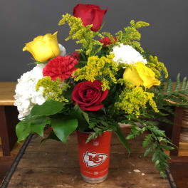 Bouquet of red, yellow, and white flowers in a red Kansas City Chiefs cup