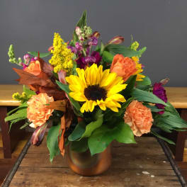 Sunflower and orange carnation arrangement in a bronze vase