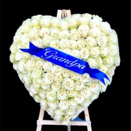 Heart-shaped bouquet of white roses with a blue ribbon on an easel