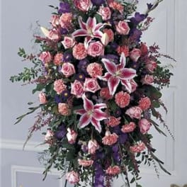 Tall standing floral spray with pink roses and lilies in pink, purple, and white.