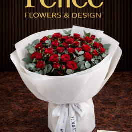Bouquet of red roses wrapped in white paper with a ribbon