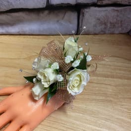 White rose corsage with gold ribbon on a mannequin hand