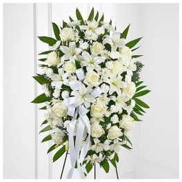 White floral standing spray with lilies and roses on an easel
