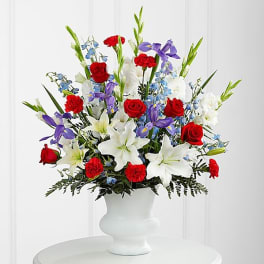 Mixed bouquet of red roses, white lilies, and purple flowers in a white vase