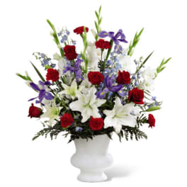 Red roses and white lilies with purple flowers in a white vase