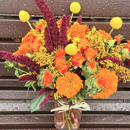 Bouquet of orange and yellow flowers in a glass jar vase