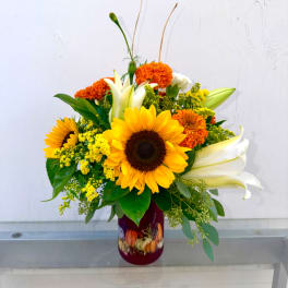 Sunflower and lily arrangement in a burgundy vase