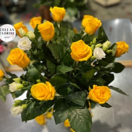 Arrangement of bright yellow roses with a few white blooms in a clustered bouquet