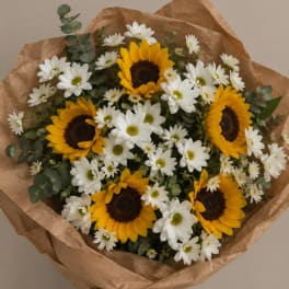 Bouquet of sunflowers and white daisies wrapped in brown paper