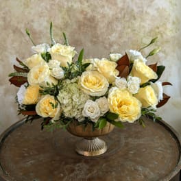 Cream and pale yellow roses arranged in a pedestal bowl