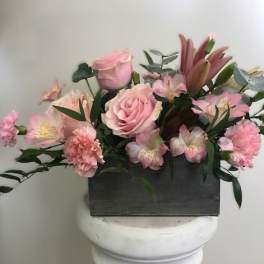 Pink roses and lilies arranged in a black rectangular container