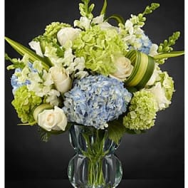 Blue and green floral arrangement in a clear glass vase