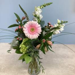 Pink gerbera daisy arrangement in a clear glass vase with white blooms