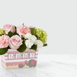 Pink and white flower arrangement in a baby-themed box