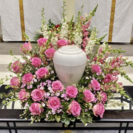 Pink roses and white snapdragons arranged around a white urn