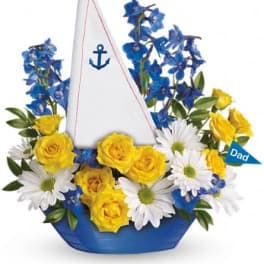 Yellow roses and white daisies arranged in a blue sailboat container