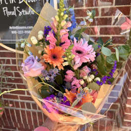 Colorful mixed bouquet with gerbera daisies, roses, and snapdragons in clear wrap
