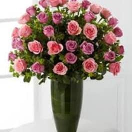 Pink and lavender roses arranged in a tall green vase