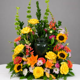 Colorful floral arrangement with yellow roses, sunflowers, and orange lilies in a dark vase