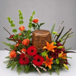 Autumn floral arrangement with orange roses, red gerberas, lilies, and a wooden urn