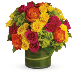 Mixed roses in yellow, pink, and orange arranged in a green glass vase.