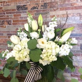 White floral arrangement with lilies, hydrangeas, and a striped ribbon