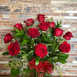 Red roses arranged in a clear glass vase with a red ribbon