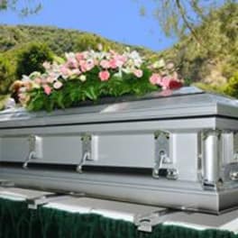 Silver casket topped with pink and white flowers