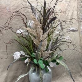 Tall arrangement of dried grasses and white accents in a gray vase