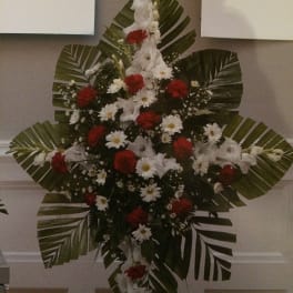 Standing floral spray with white and red flowers and large palm leaves