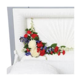 Floral casket spray with red, white, and blue flowers on a white casket