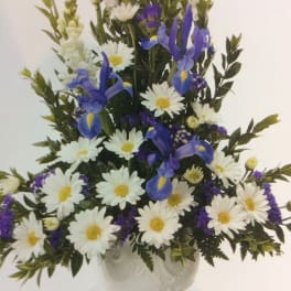 White daisies and blue irises arranged in a clear vase