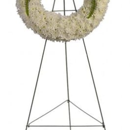 Standing funeral wreath with red roses, white flowers, and blue accents on an easel