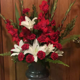 Red carnations and white lilies arranged in a black vase