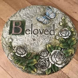 Decorative stone plaque with roses, a butterfly, and the word "Beloved"