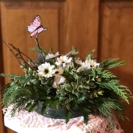 Low floral arrangement with white daisies and a pink butterfly pick
