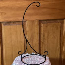 Black metal hanging stand with curled hooks on a pedestal