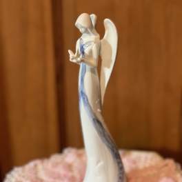 White angel figurine with blue accents on a pink floral base