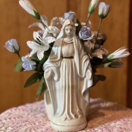 Ceramic statue surrounded by small white and lavender flowers