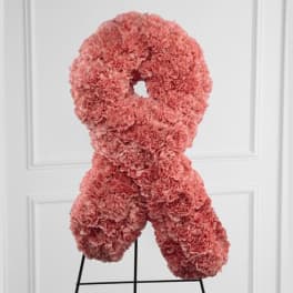Pink carnation ribbon-shaped floral tribute on a stand