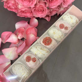 Pink rose bouquet with a box of decorated sweets and scattered petals