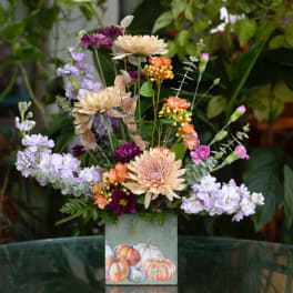 Mixed bouquet in a square vase with pastel and orange blooms