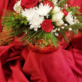 Red and white floral arrangement in a gold basket on red fabric