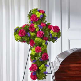 Cross-shaped floral tribute with pink roses and bright mixed blooms