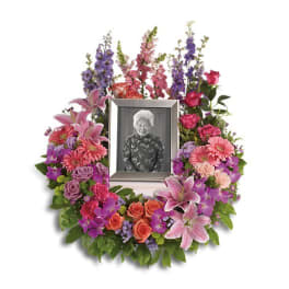 Sympathy wreath of pink and purple flowers around a framed photo
