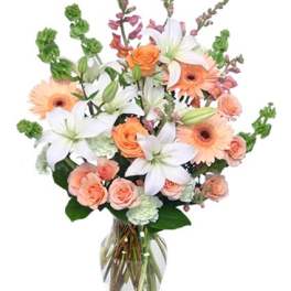 Peach and white flower bouquet in a clear glass vase
