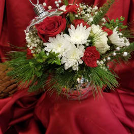 Red and white floral arrangement in a clear ornament-shaped vase